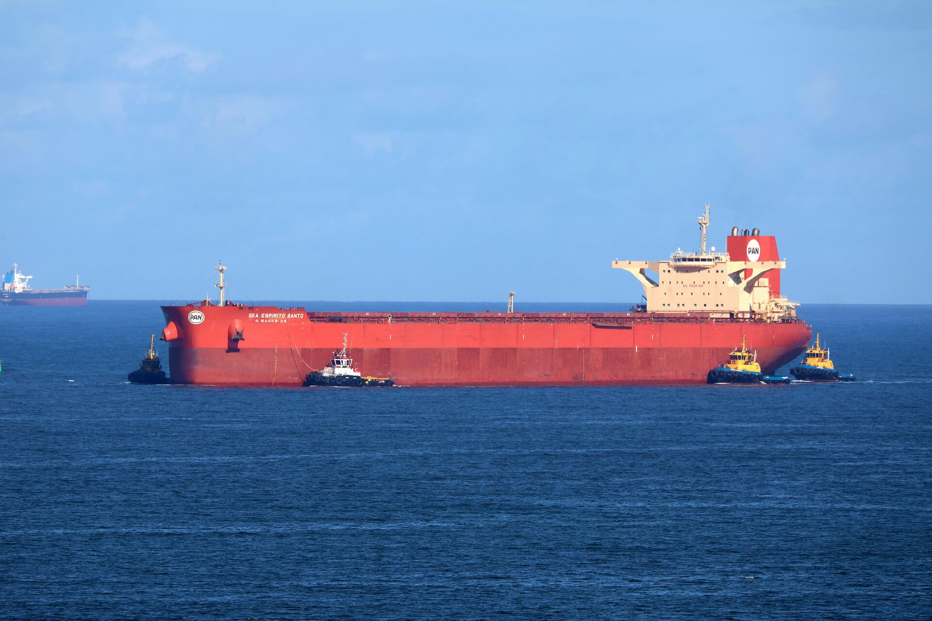 Tanker at anchor with support tugs